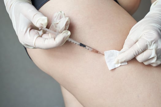 close up of injection procedure in medical setting with gloved hands administering shot on adult skin. photo