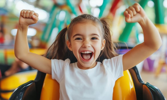 Excited young girl raising arms on roller coaster ride capturing joy and fun in an amusement park setting photo