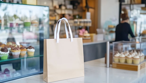 Tan paper shopping bag on marble counter in bakery with cupcakes and desserts photo