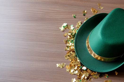 Green hat with shamrock confetti on wood background overhead flat lay photo
