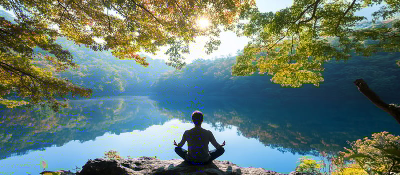 Person meditating by lake surrounded by trees nature serenity photo