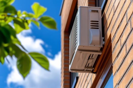 Residential air conditioner mounted on brick exterior under blue sky photo