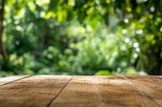 Rustic wooden table with blurred green foliage background for product mockups photo