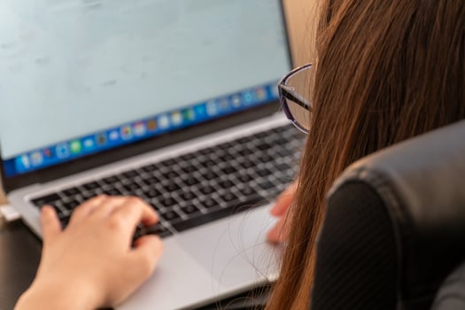 A woman is typing on a laptop computer photo