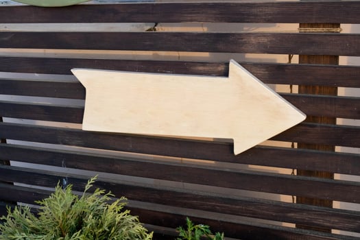 A wooden white arrow pointer with no inscription on a brown plank background photo