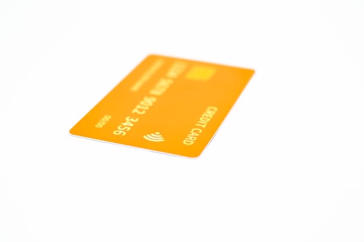 Close-up studio shot of a vibrant orange credit card with contactless payment symbol isolated on white background photo