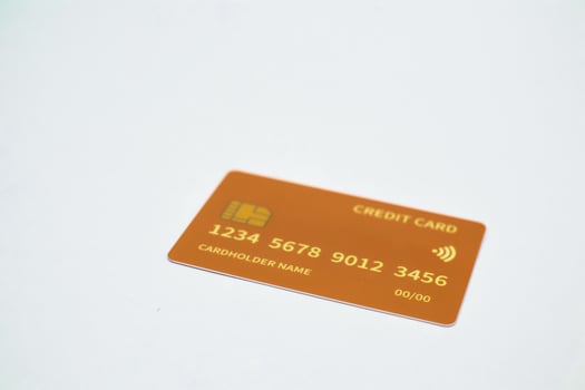 Orange credit card with chip and contactless payment symbol on white background, financial instrument photo