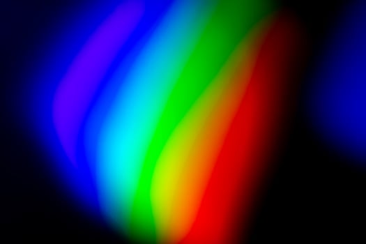A rainbow colored light is shown in the dark photo