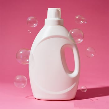 A white plastic bottle of liquid with soap bubbles on a pink background photo