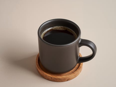 A black coffee cup on a wooden coaster photo