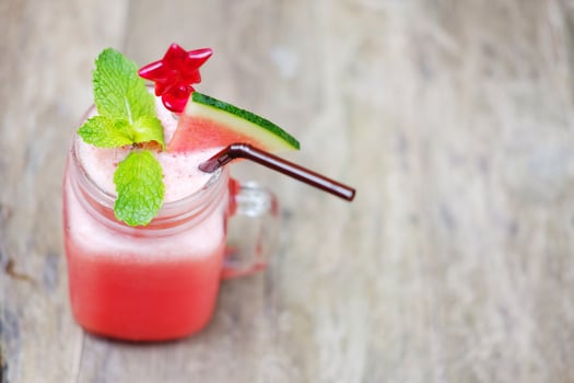 Top view of a glass of watermelon smoothie with red star spoon on wooden table in tropical of cafe. Copy space photo
