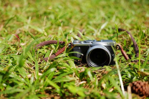 Vintage mirrorless camera on green lawn grass field in natural sunlight shining day in garden photo