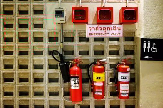 Emergency valves in Thai characters on a white sign with red fire extinguisher and toilet label on concrete wall photo