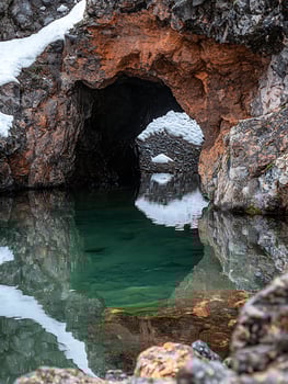 Mysterious Cave Entrance Reflected in Clear Mountain Pool. photo