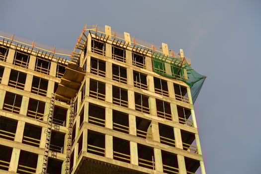 Modern concrete building under construction, with exposed framework, scaffolding, and safety nets, signifying urban development, real estate, and future growth photo