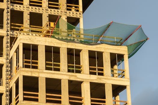 Concrete high-rise building under construction showing empty window frames, wooden elements, and protective safety netting, signifying urban development photo