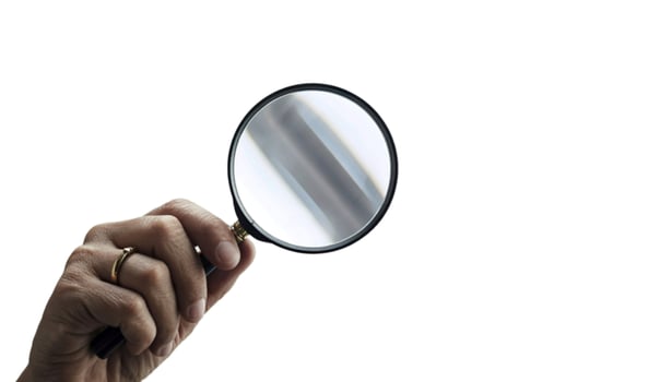 Hand holding a magnifying glass to examine something closely photo