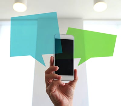 Hand holding a smartphone with colorful speech bubbles representing communication photo