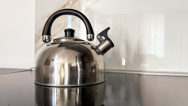 A sleek stainless steel kettle reflects morning light, evoking Hygge comfort and International Tea Day anticipation photo