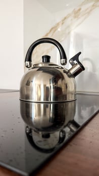 Shiny kettle gleams like lunar metal on stovetop, evoking cozy tea rituals and cozy Hygge inspired gatherings photo
