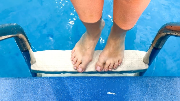 Balancing on a diving board, anticipating splash thrills, reminiscent of mermaid festivals, summertime solstice adventures, diversity in motion photo