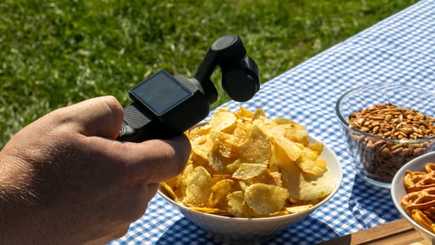 A hand with digital prowess hovers over sunlit crisp chips, capturing National Picnic Day excitement, tech meets taste photo