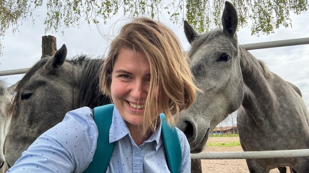 Smiling woman with playful horses, equine joy on St Stephens Day, celebrating harmony with nature and rural serenity photo