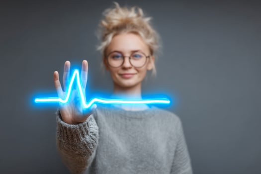 Woman in glasses holding up a heartbeat sign photo