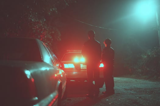 Two men standing next to a car at night photo