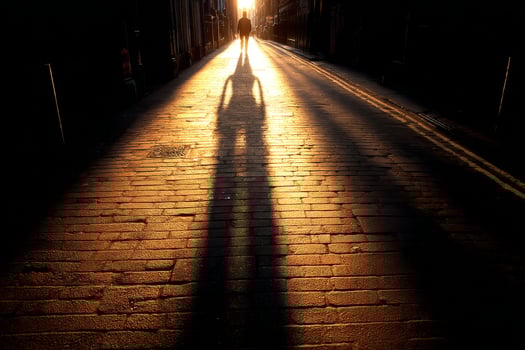 A person walking down a street with the sun setting behind them photo