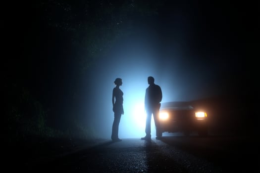 A man and woman standing in front of a car at night photo