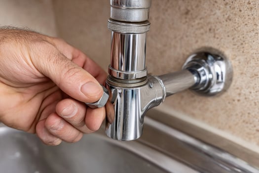 A person is fixing a faucet in a kitchen sink photo