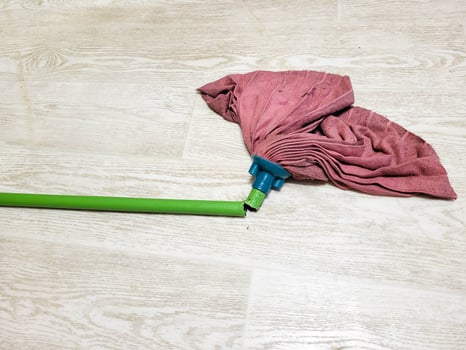 A dirty pink microfiber floor cloth on a broken green mop. photo