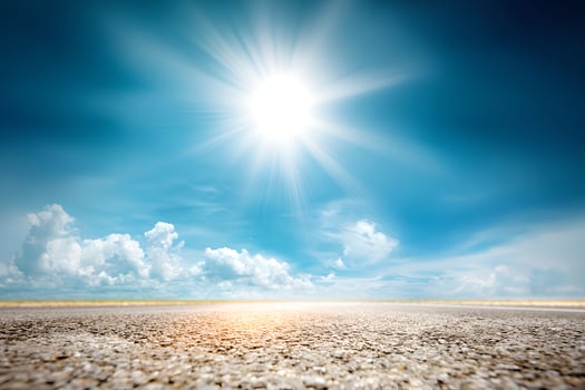 The sun shining over a dry road photo