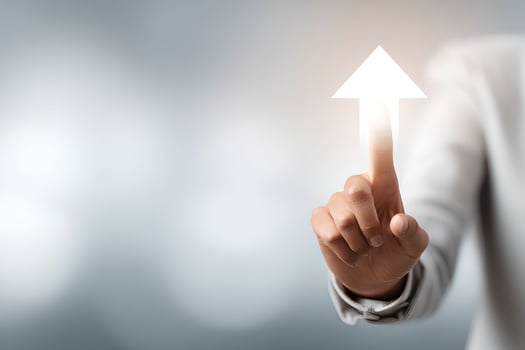 A person in a business suit is pointing at an arrow pointing up photo