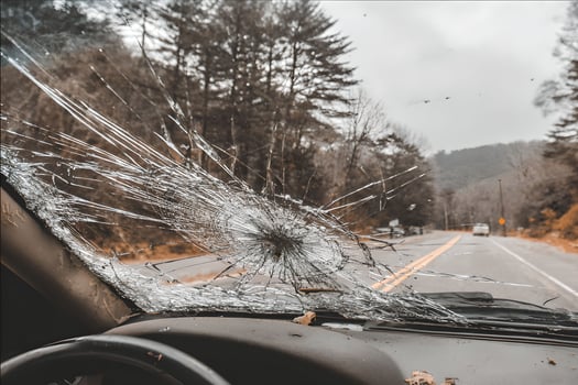 A windshield with a shattered window and a car driving down the road photo
