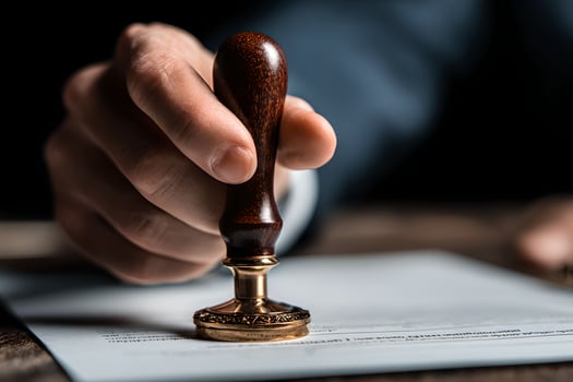 A person in a suit holding a stamp on a piece of paper photo