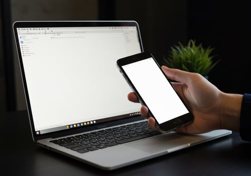 Laptop and Mobile Phone with Blank Screens on a Dark Desk with Plant photo