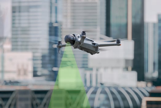 Professional drone flying in urban environment with visible green sensor beam for obstacle detection and navigation photo
