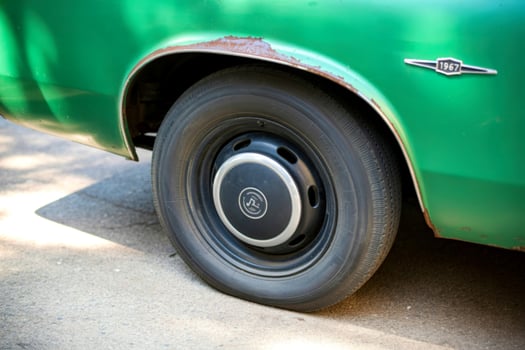 Close up of a vintage green car s wheel and fender with rust detail photo