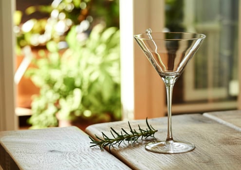 Elegant martini glass with rosemary garnish on a wooden table photo