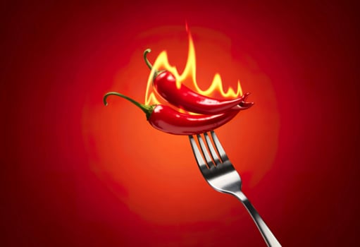 Red chili peppers on a fork with fire on a red gradient background photo