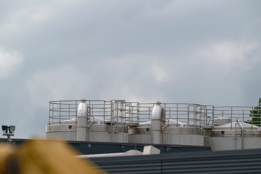 Three large industrial silos connected by pipes and ladders under cloudy sky photo