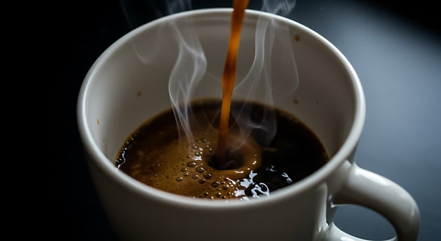 Pouring Hot Drink Into a Mug with Steam on Dark Surface photo