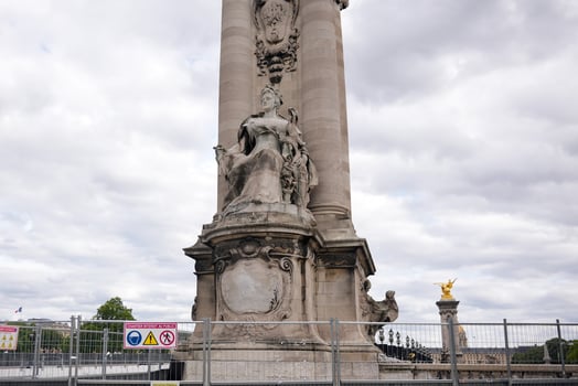 Pont Alexandre III stone column with sculptures and cloudy sky in Paris France photo