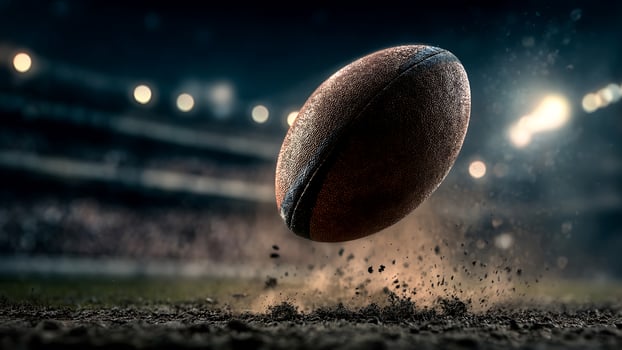 Dramatic close-up of an American football kicking up dirt on a stadium field at night. photo
