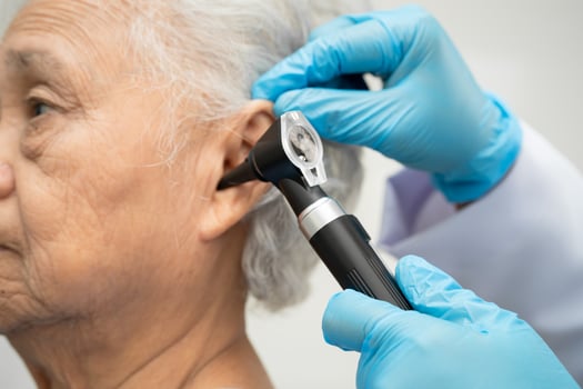 Otolaryngologist or ENT doctor examining senior patient ear with otoscope hearing loss photo