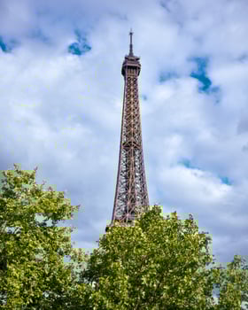 Eiffel Tower in Paris France against a blue sky with green trees photo