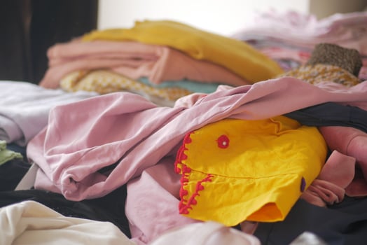 Pile of assorted clothes on a bed waiting to be organized photo
