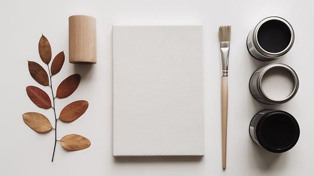 A white notebook, paint, brush and leaf on a table photo